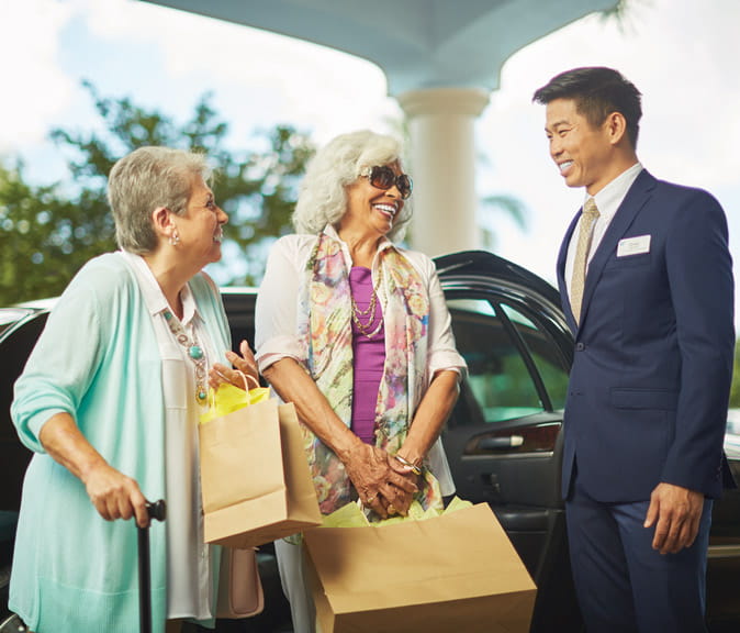 A valet assists women who are returning from a shopping trip.