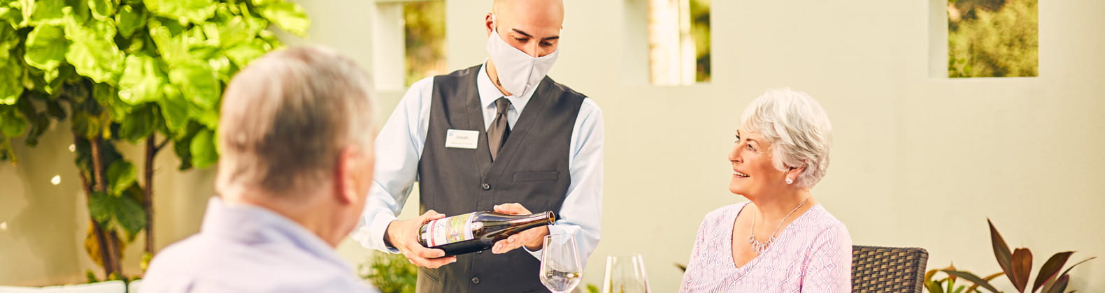A server wearing a mask pours wine.